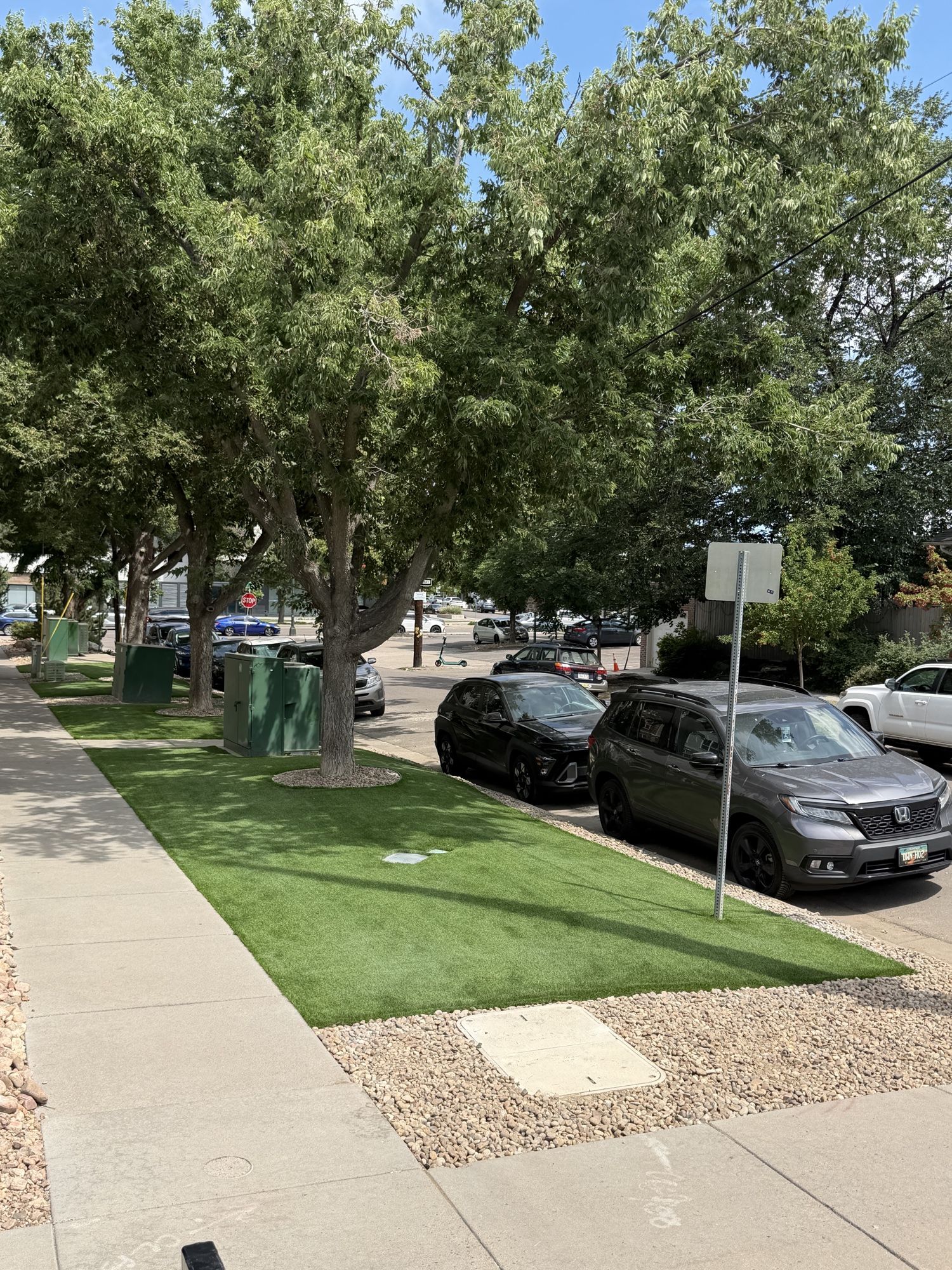 Strip of artificial turf installed neatly between a concrete sidewalk and the street curb