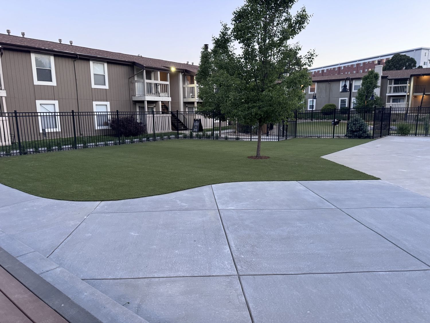 Smooth concrete patio meeting an artificial turf area at an apartment complex