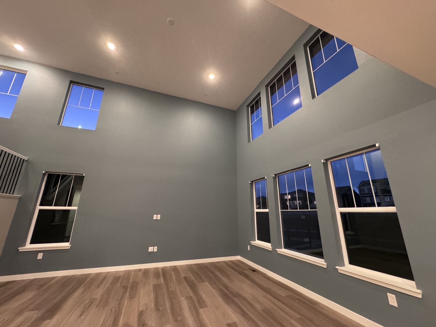 Room with high ceilings and light wood floors featuring freshly painted blue-grey walls